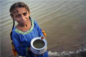 Mädchen mit einer Schüssel Wasser am Ufer eines Flusses