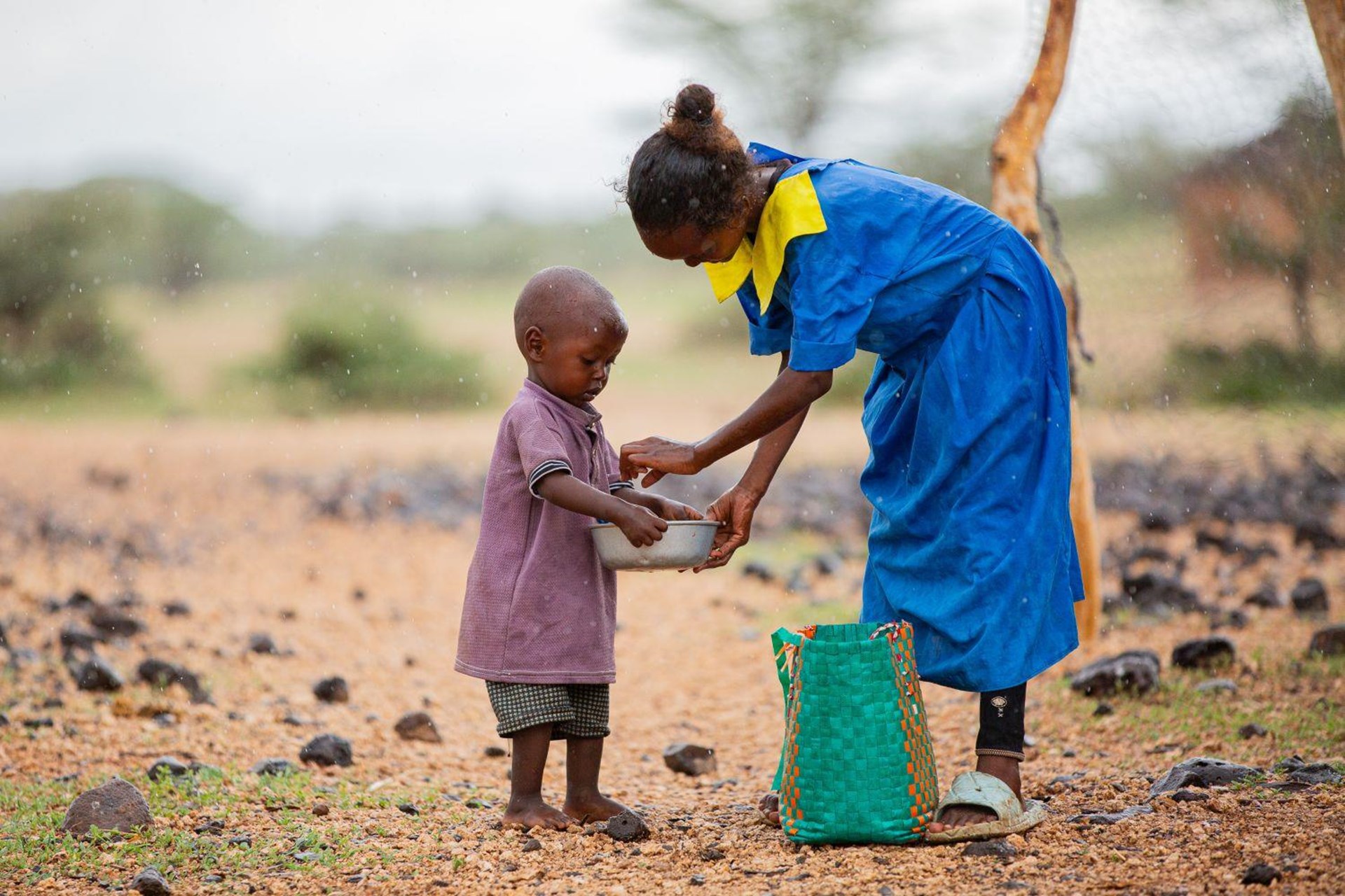 Kenia: Ein Mädchen gibt ihrer kleinen Schwester einen Teller voll Essen.