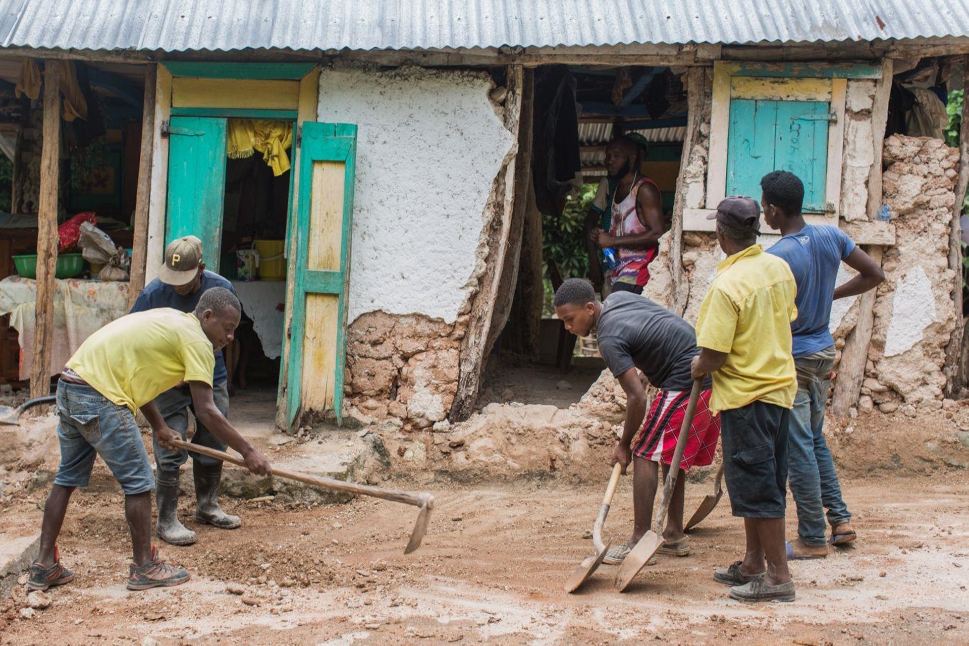 Eine Gruppe junger Männer versucht mit Hilfe von Schaufeln eine Straße nach dem Erdbeben in Haiti wieder instand zu setzen