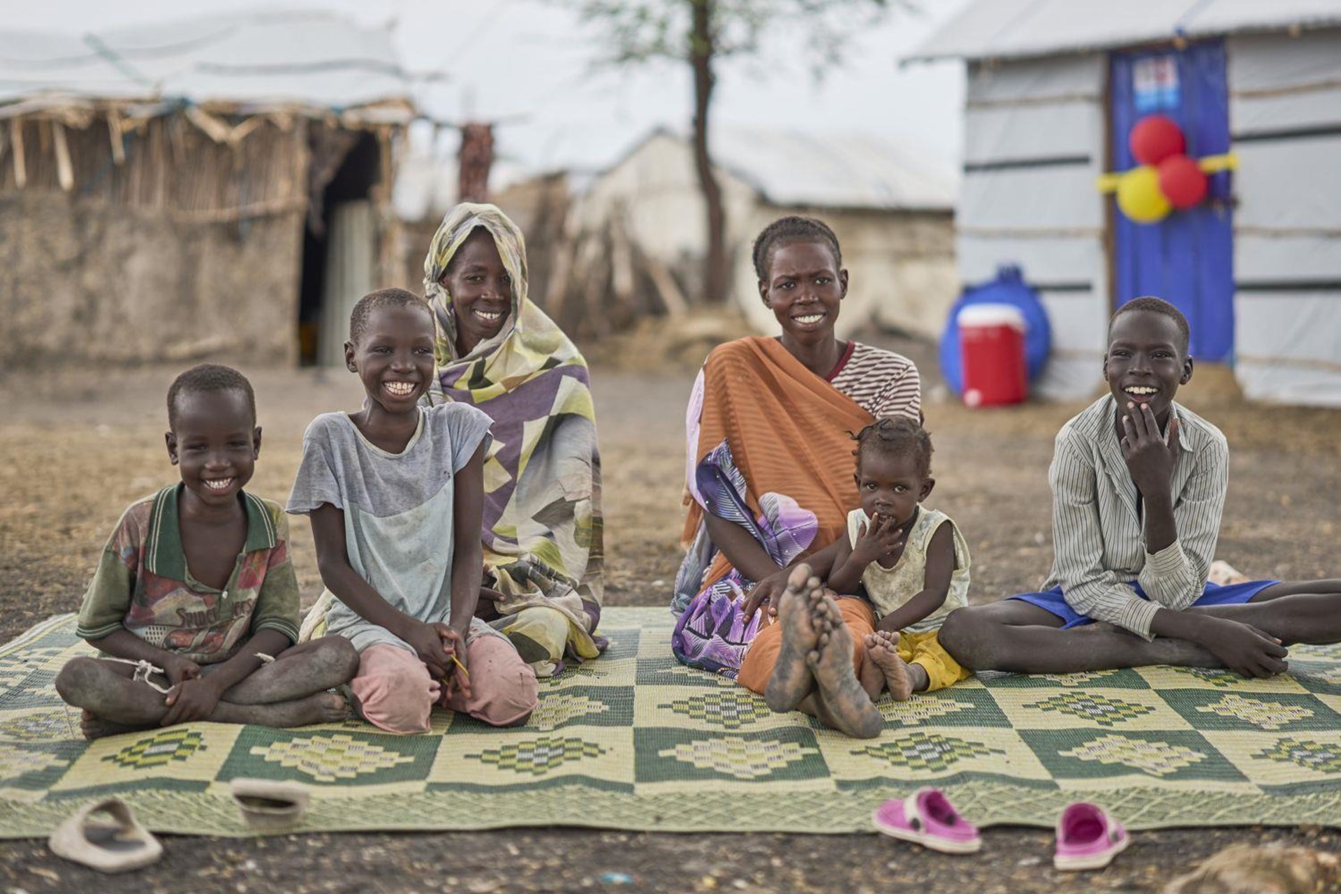 Zwei Frauen sitzen mit ihren Kindern vor ihrem Haus in Kodok, Südsudan