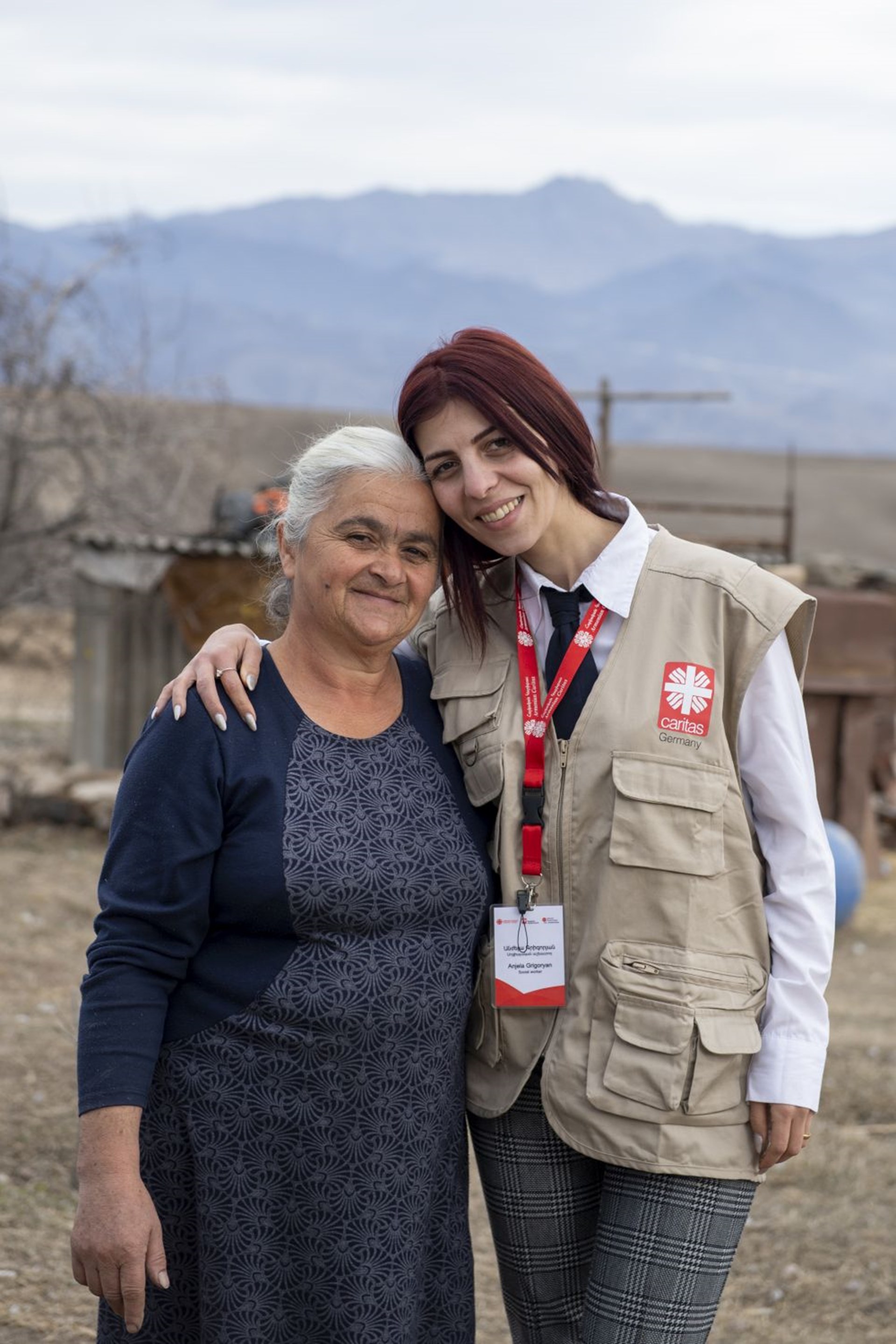 Eine Caritasmitarbeiterin legt den Arm um eine Frau