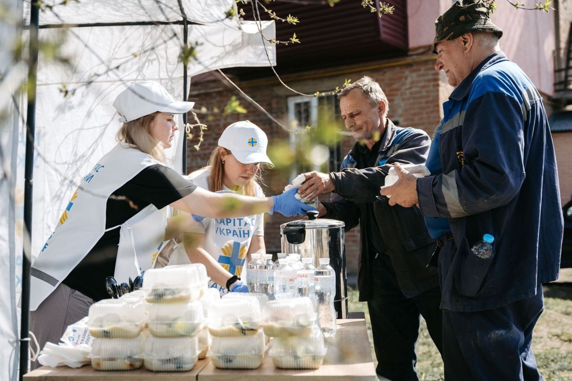 Caritas-Mitarbeiterinnen verteilen warme Mahlzeiten an Menschen in Poltawa.