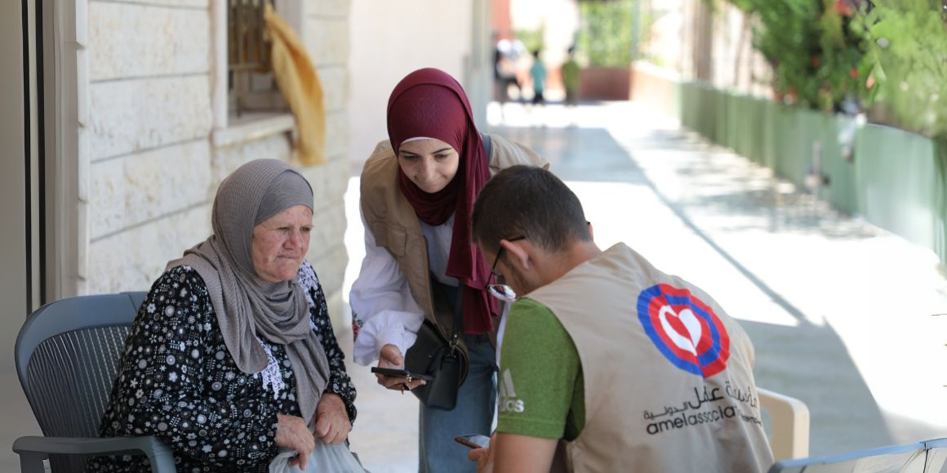 Ein Mitarbeitender der Partnerorganisation Amel Association International bei einem Besuch einer älteren Frau im Süden des Libanon.