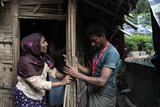 Ein Caritas-Mitarbeiter hilft Toyaba_Khatun, eine geflüchtete Rohingya, bei der Renovierung ihrer Hütte in Kutupalong