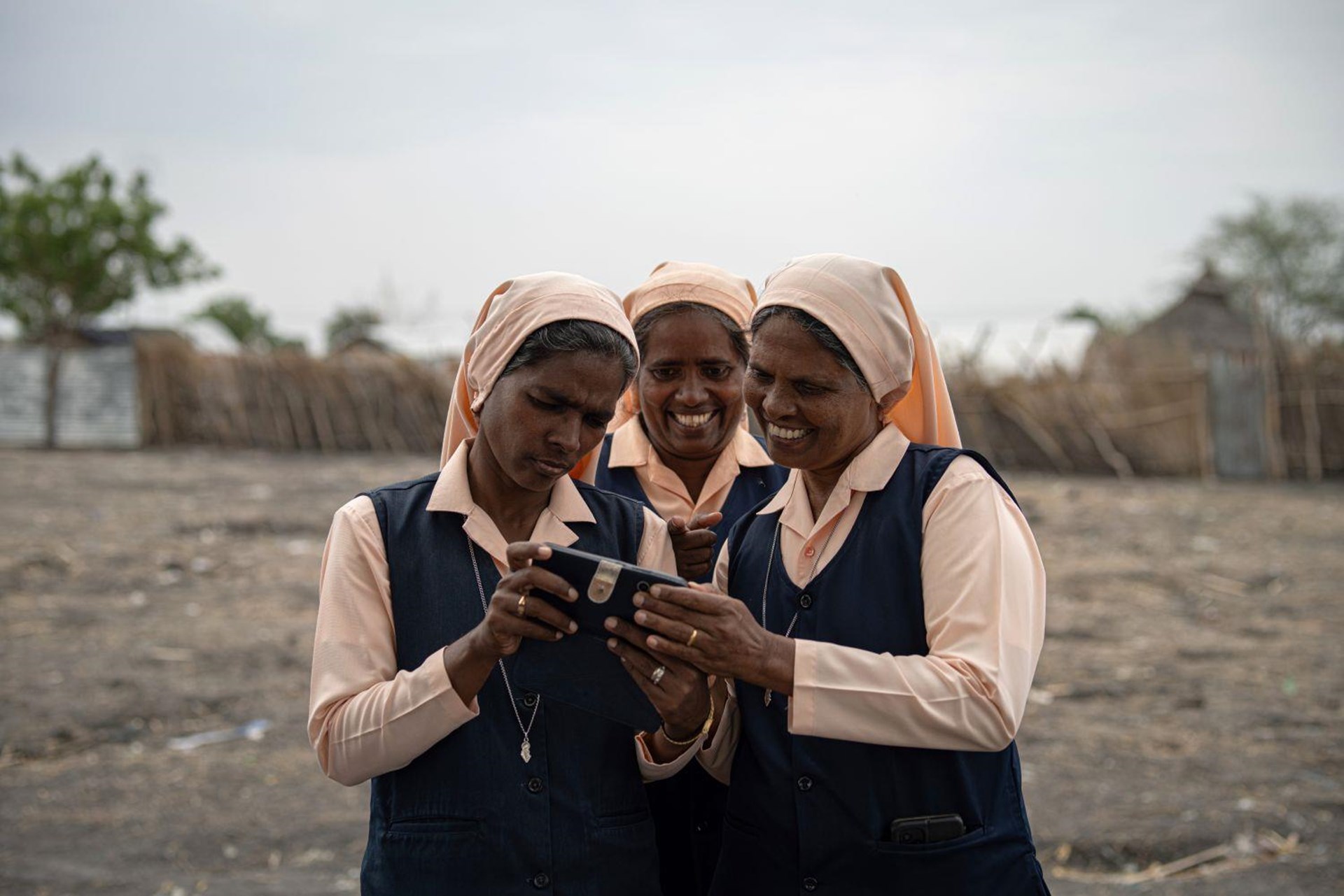 Drei DMI-Sisters schauen gemeinsam auf ein Handy.