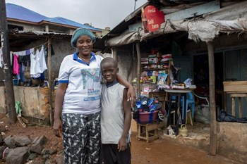 Kadiatu Bargura vor ihrem Laden in Goodrich Community (Freetown) gemeinsam mit ihrem Adoptivson Samdora.