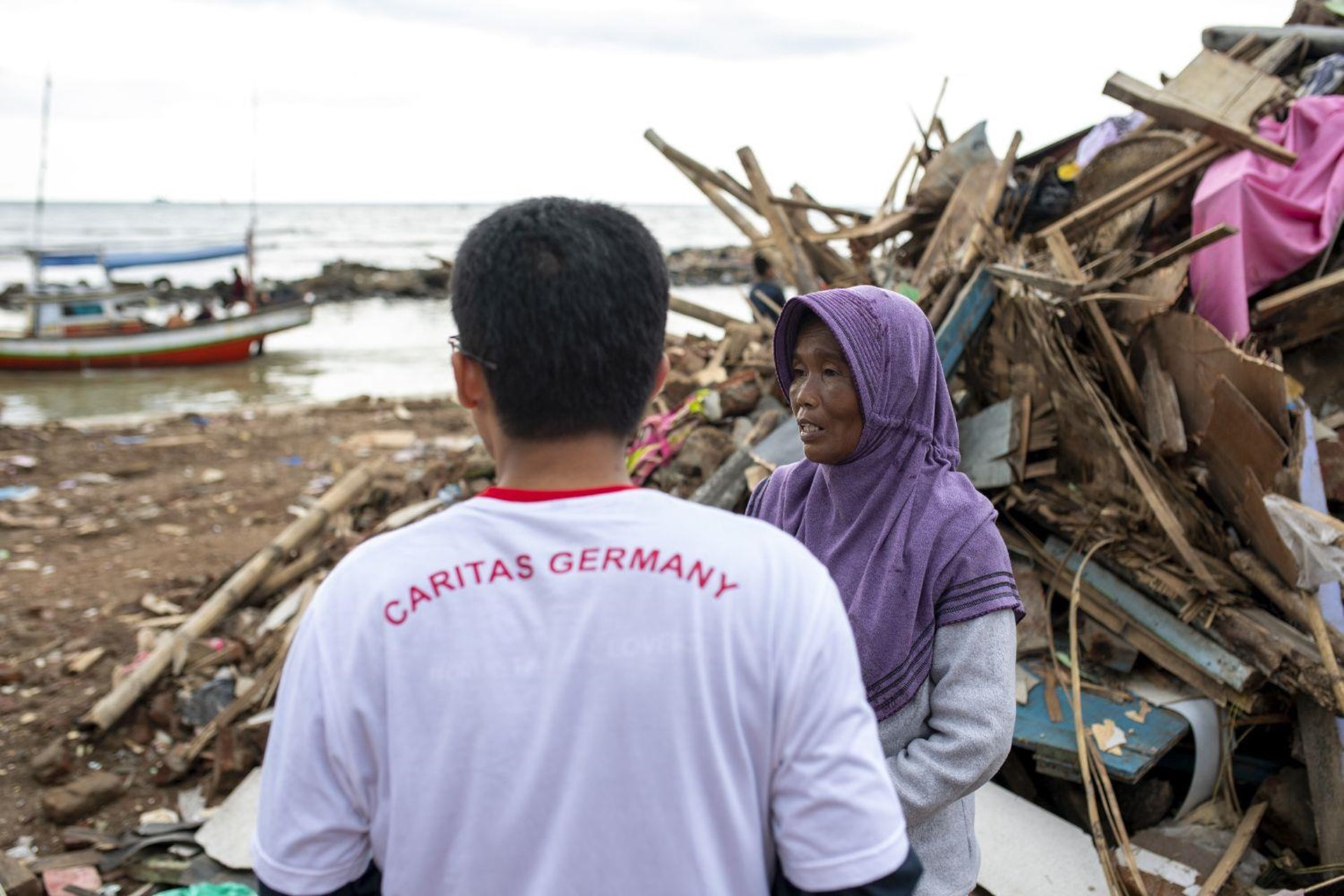 Ein Caritas-Helfer unterstützt eine Frau in Indonesien nach dem Erdbeben.